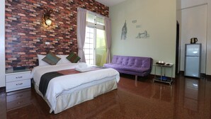 A hotel room with a brick wall, a bed with white bedding, a purple sofa, a small table with a kettle, and a refrigerator. - Mozhu B&B (Hualien City)
