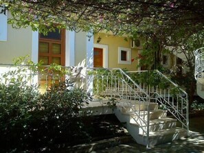 A staircase with a metal railing leading to a building with a yellow facade and a window with a wooden frame.