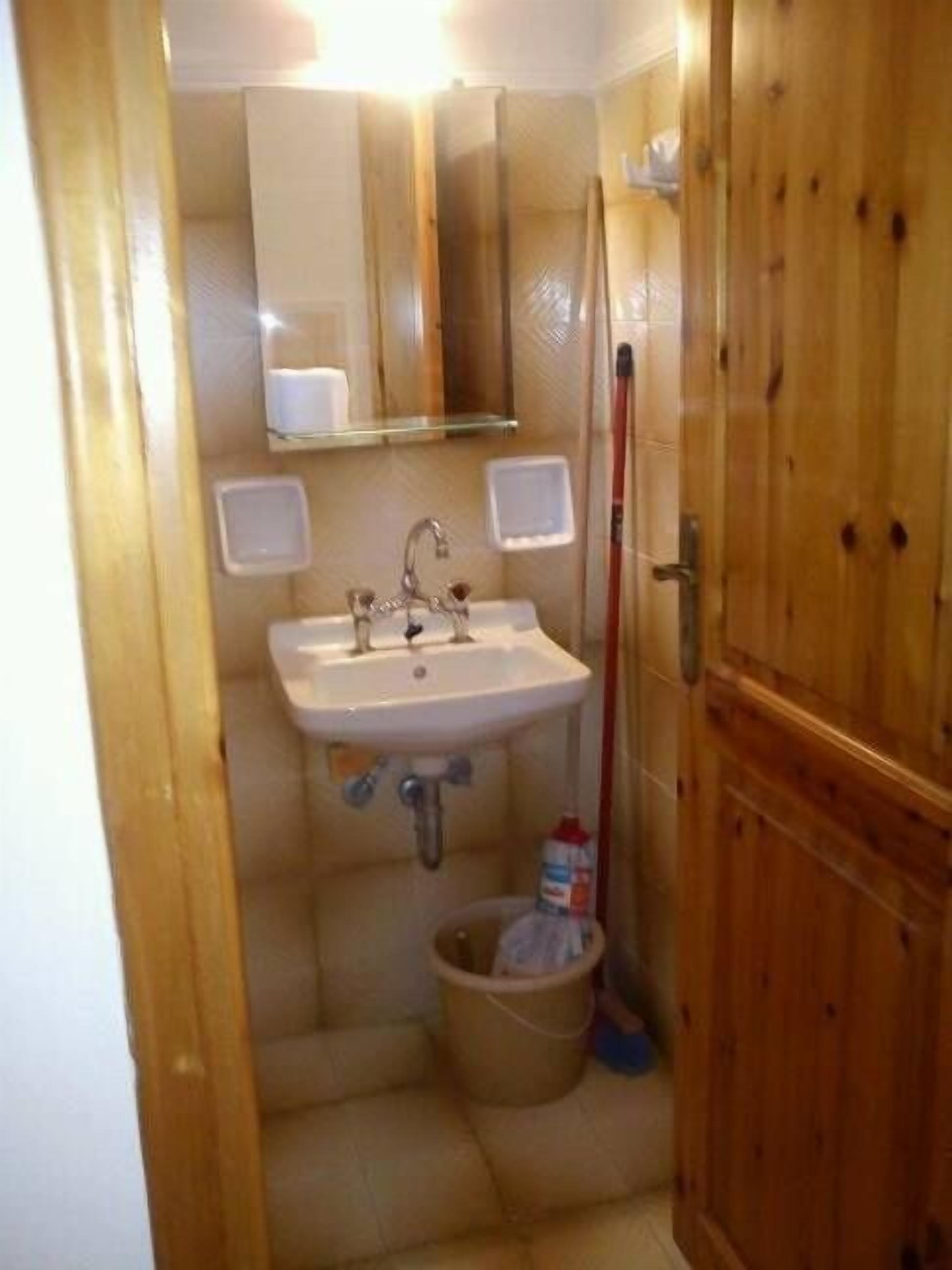 Ein kleines Badezimmer mit Waschbecken, Spiegel und Holztür.