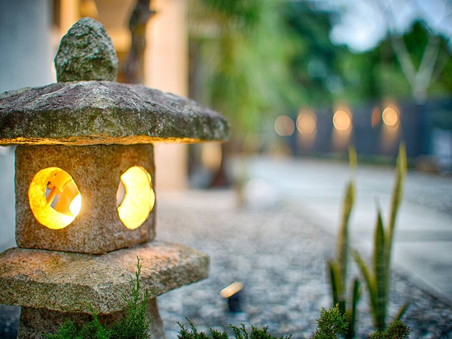 A stone lantern with two glowing windows, set on a stone base with moss.