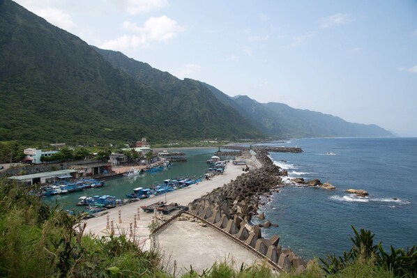 A coastal marina with boats docked, a rocky breakwater, and mountainous terrain in the background. - Ruisui Sunshine Hot Spring B&B (Ruisui)
