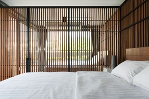 A modern bedroom with a large bed, wooden slats, and a view of the outdoors. - Nord Studio (Chiang Mai)