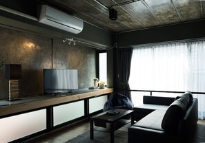 A modern living room with a sofa, a coffee table, and a TV on a wooden shelf. - Nord Studio (Chiang Mai)