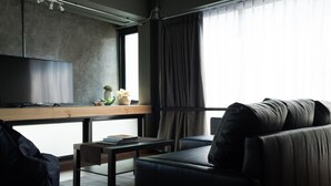 Un salon moderne avec un canapé, une table basse, un téléviseur et une fenêtre avec des rideaux.