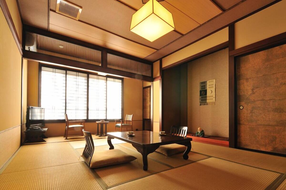 A traditional Japanese room with tatami flooring, a low table, and sliding doors.