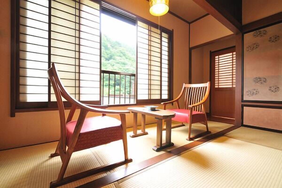 A traditional Japanese room with tatami flooring, shoji screens, and wooden furniture.
