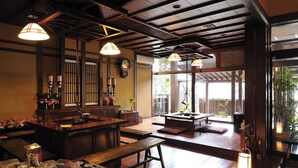 Un interior japonés tradicional con vigas de madera, suelo de tatami y una zona de bar con botellas de sake.