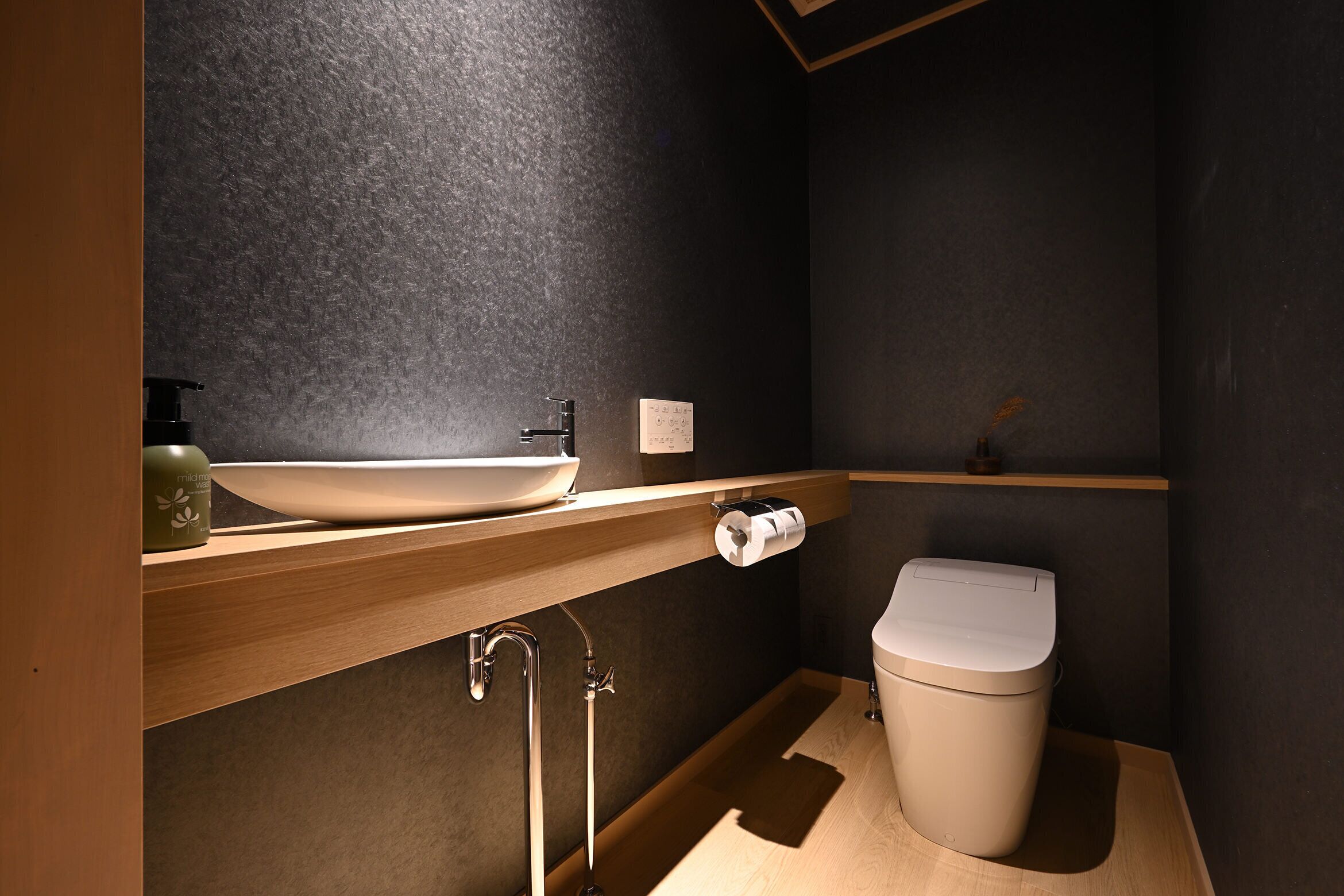 Een moderne badkamer met een houten wastafelmeubel, een witte wasbak en een toilet.