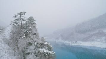 Un paisaje montañoso nevado con un lago azul cristalino y un puente colgante.