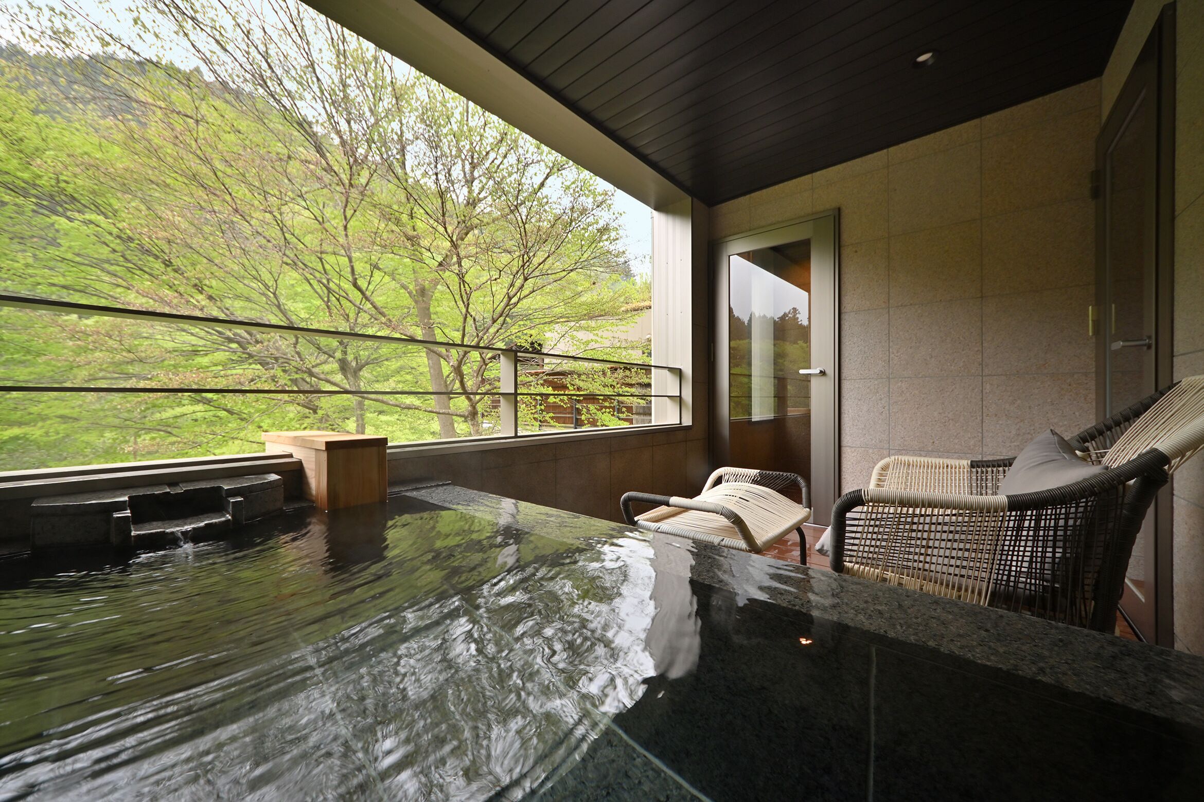 Un jacuzzi con vistas a un jardín exuberante y una silla de mimbre.