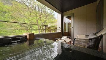 Un jacuzzi con vistas a un jardín exuberante y una silla de mimbre.
