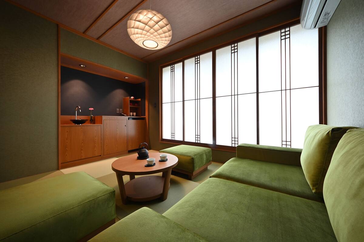A traditional Japanese-style room with tatami flooring, a low table with a tea set, and a large shoji screen window.