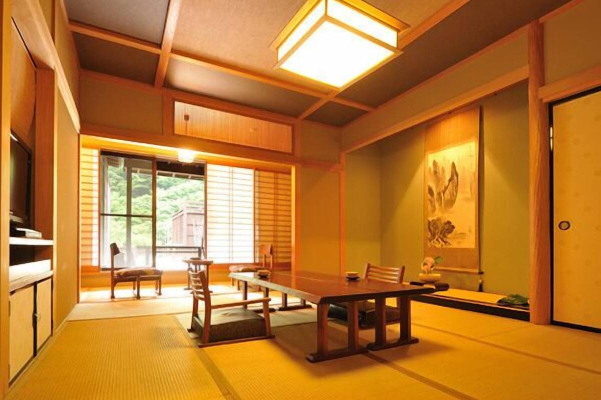 A traditional Japanese room with tatami flooring, a low table, chairs, and sliding doors.