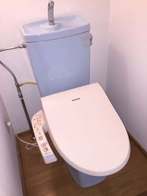 Des toilettes équipées d’un panneau de commande, d’un réservoir d’eau et d’une canalisation.