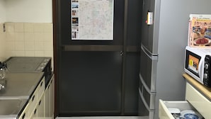 A compact kitchen with a stove, microwave, refrigerator, and a wall-mounted map. - Kyoto Guesthouse Oyado KEI (Kyoto)