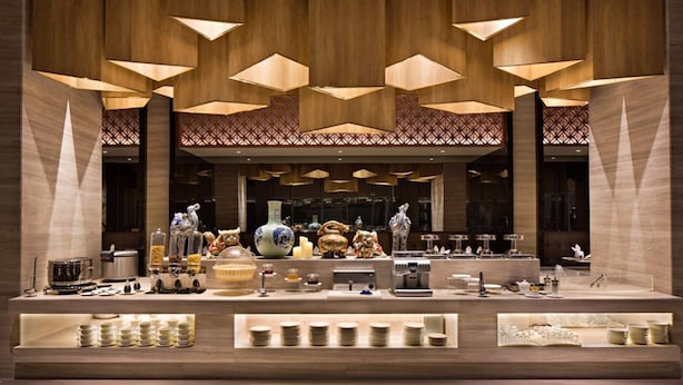 Een goed verlicht buffet met een ruim aanbod aan eten en drinken, waaronder een koffiezetapparaat en verschillende borden en kommen.