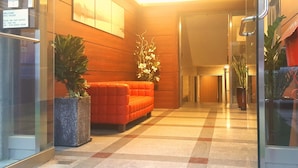 Una hall con una reception, un divano rosso e piante in vaso.
