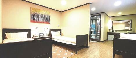 A hotel room with two beds, a desk, a chair, a bathroom visible through an open door, and a painting on the wall.
