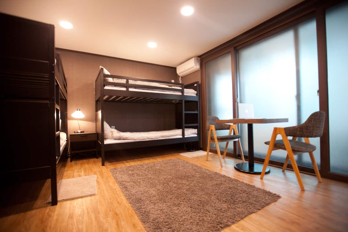 A compact room with a bunk bed, a desk with a chair, and a window with a view.
