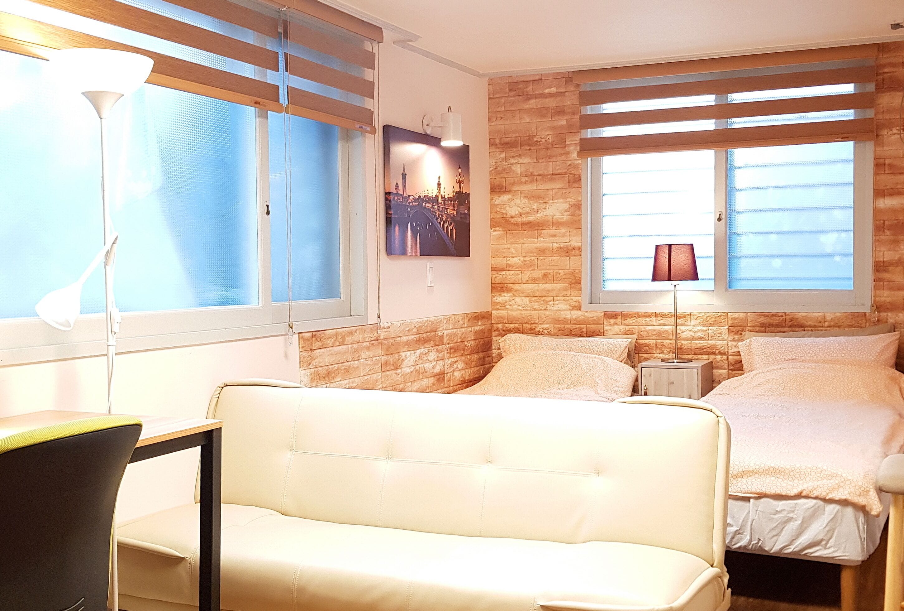 Una habitación de hotel con cama, sofá, escritorio y lámpara.