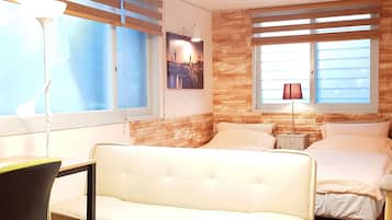 Una habitación de hotel con cama, sofá, escritorio y lámpara.