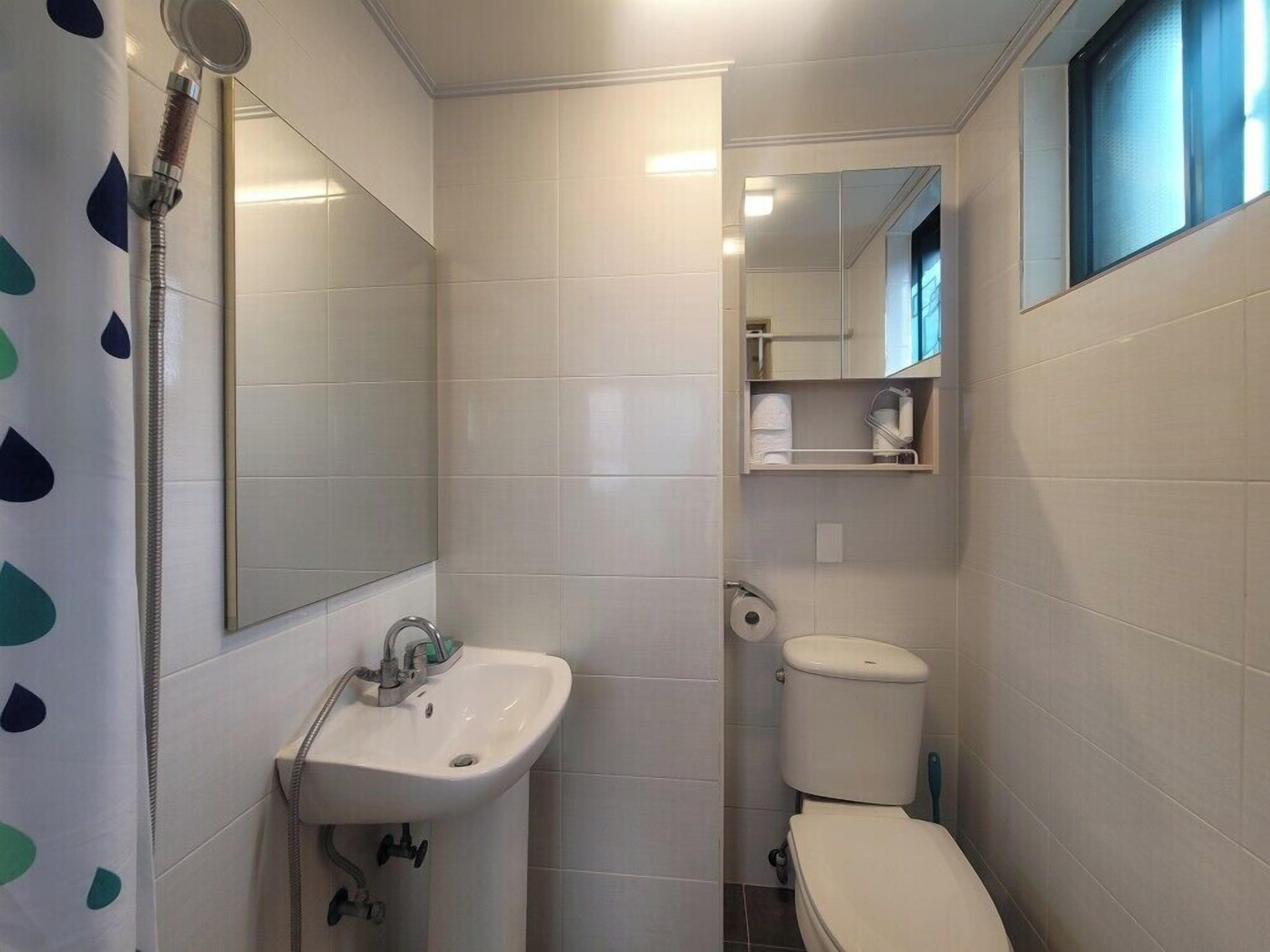 A small bathroom with a sink, toilet, and mirror.