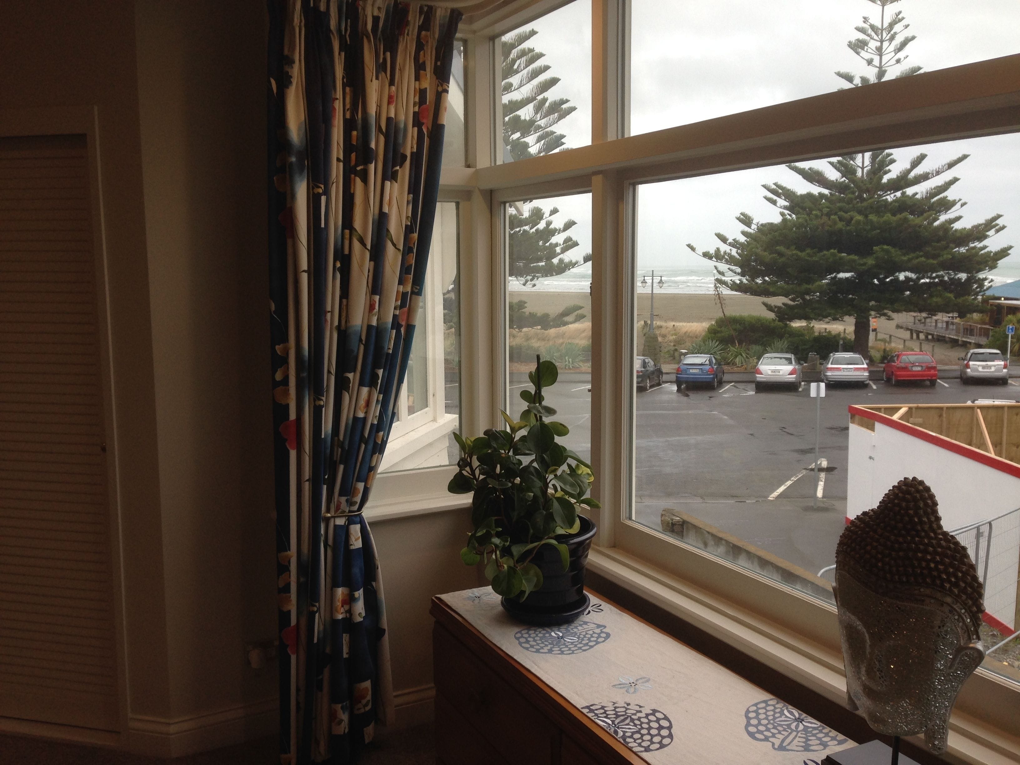 A room with a large window overlooking a parking area and a beach.