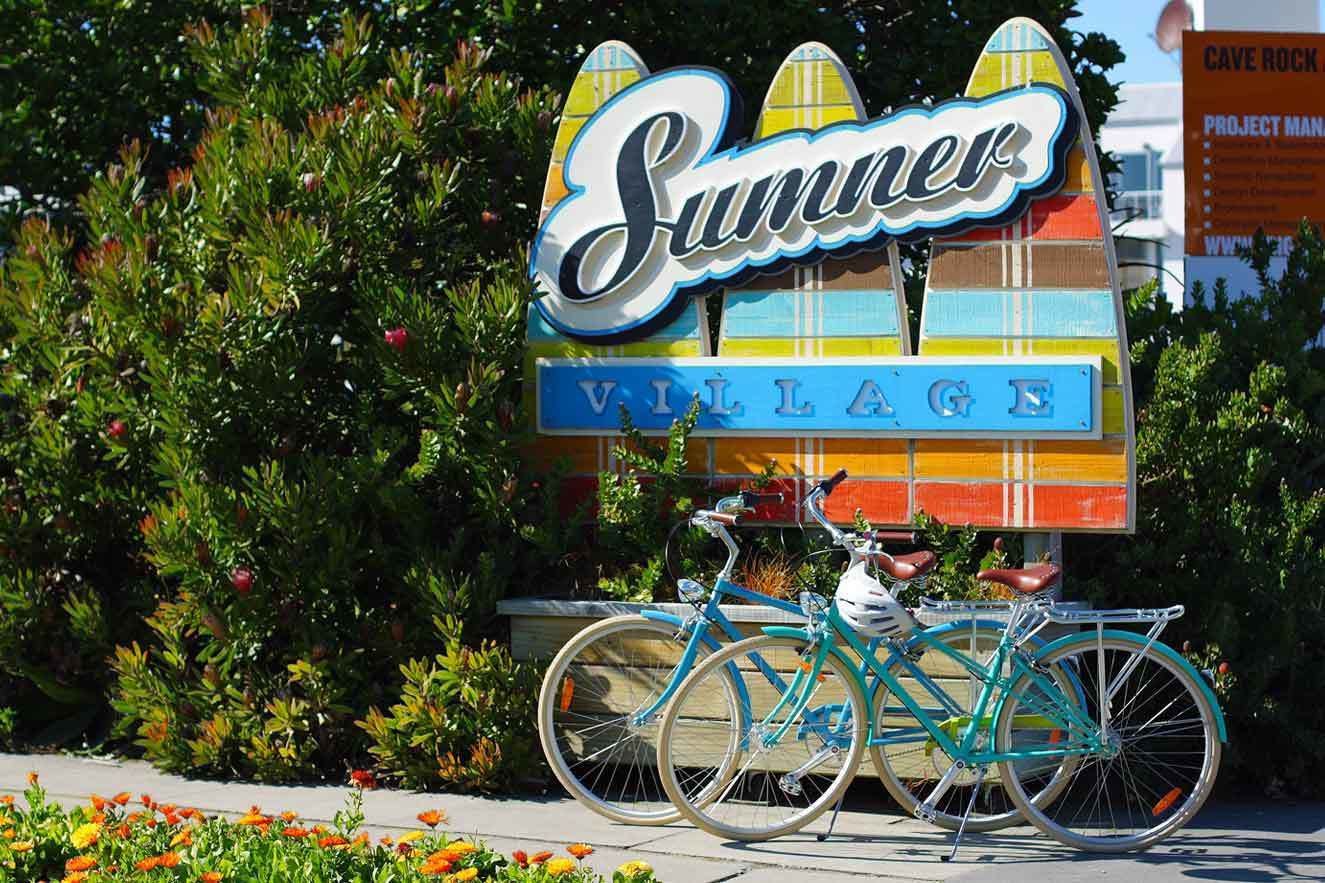 Schild für 'Summer Village', davor ein Fahrrad geparkt.