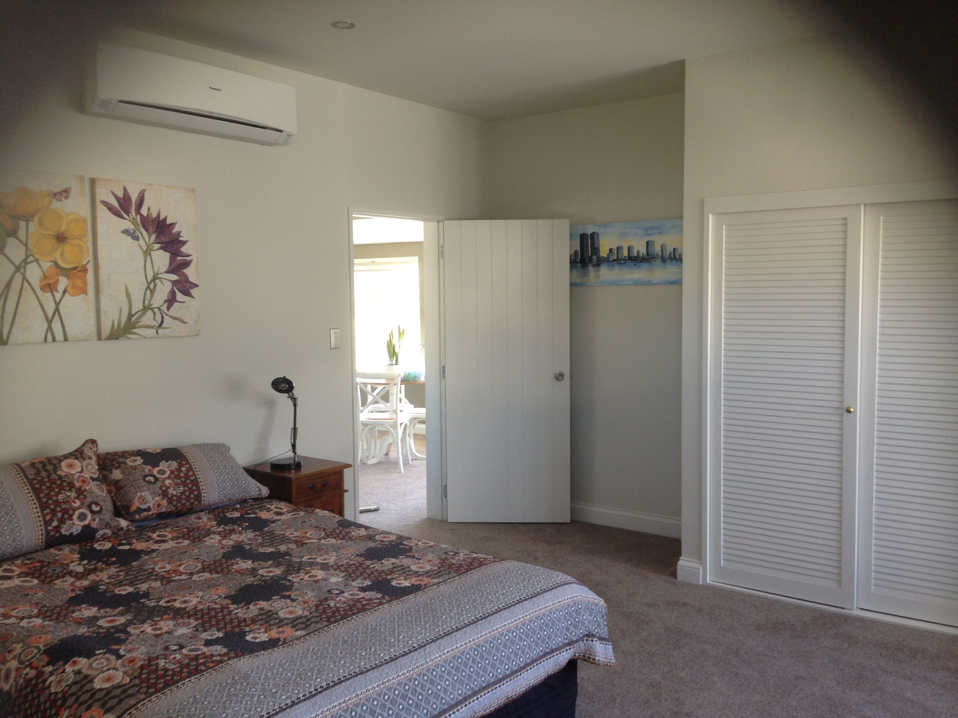 A bedroom with a bed, a desk, and a door leading to a balcony.