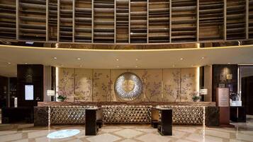 Uma área de recepção com balcão de check-in, parede decorativa com design circular e parede estampada atrás do balcão.