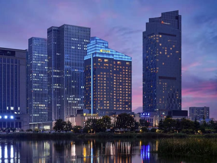 Panorama urbano con moderni grattacieli, una distesa d'acqua che riflette gli edifici e un cielo sereno.