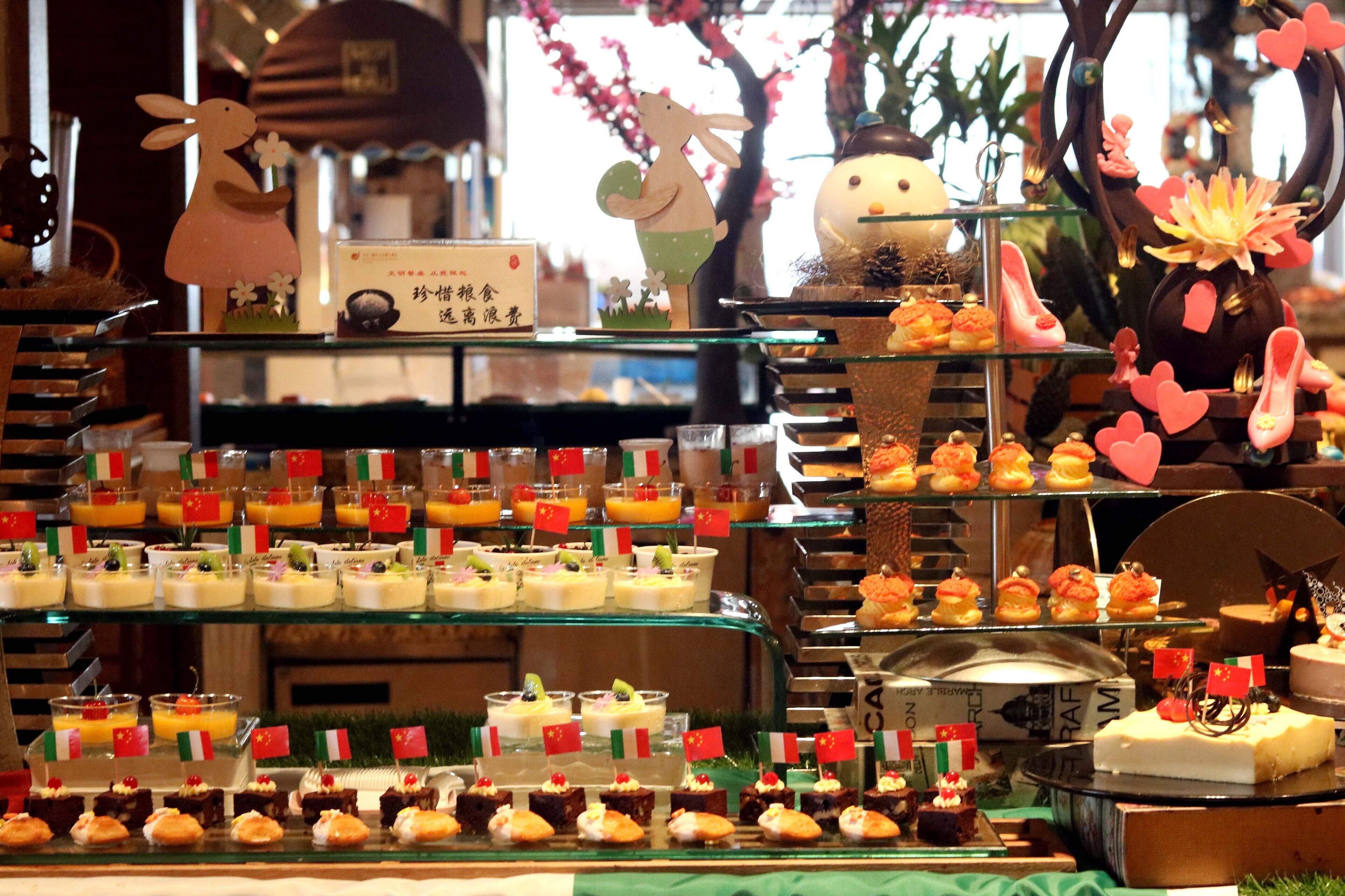 Una presentación de postres con diversos dulces y pasteles, algunos adornados con pequeñas banderas.