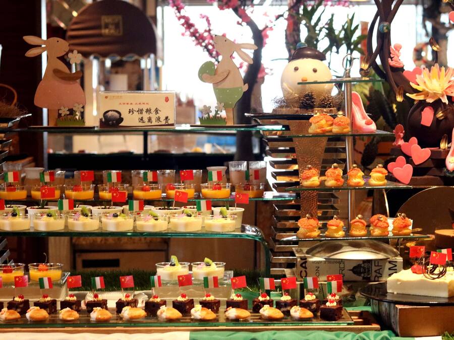 Una presentación de postres con diversos dulces y pasteles, algunos adornados con pequeñas banderas.