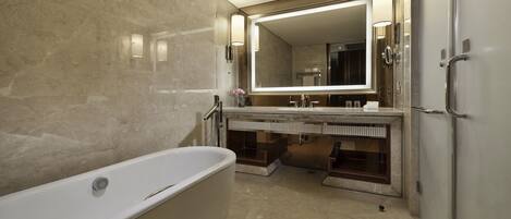 A modern bathroom with a freestanding bathtub, a large mirror, and a vanity with a sink and towel rack.
