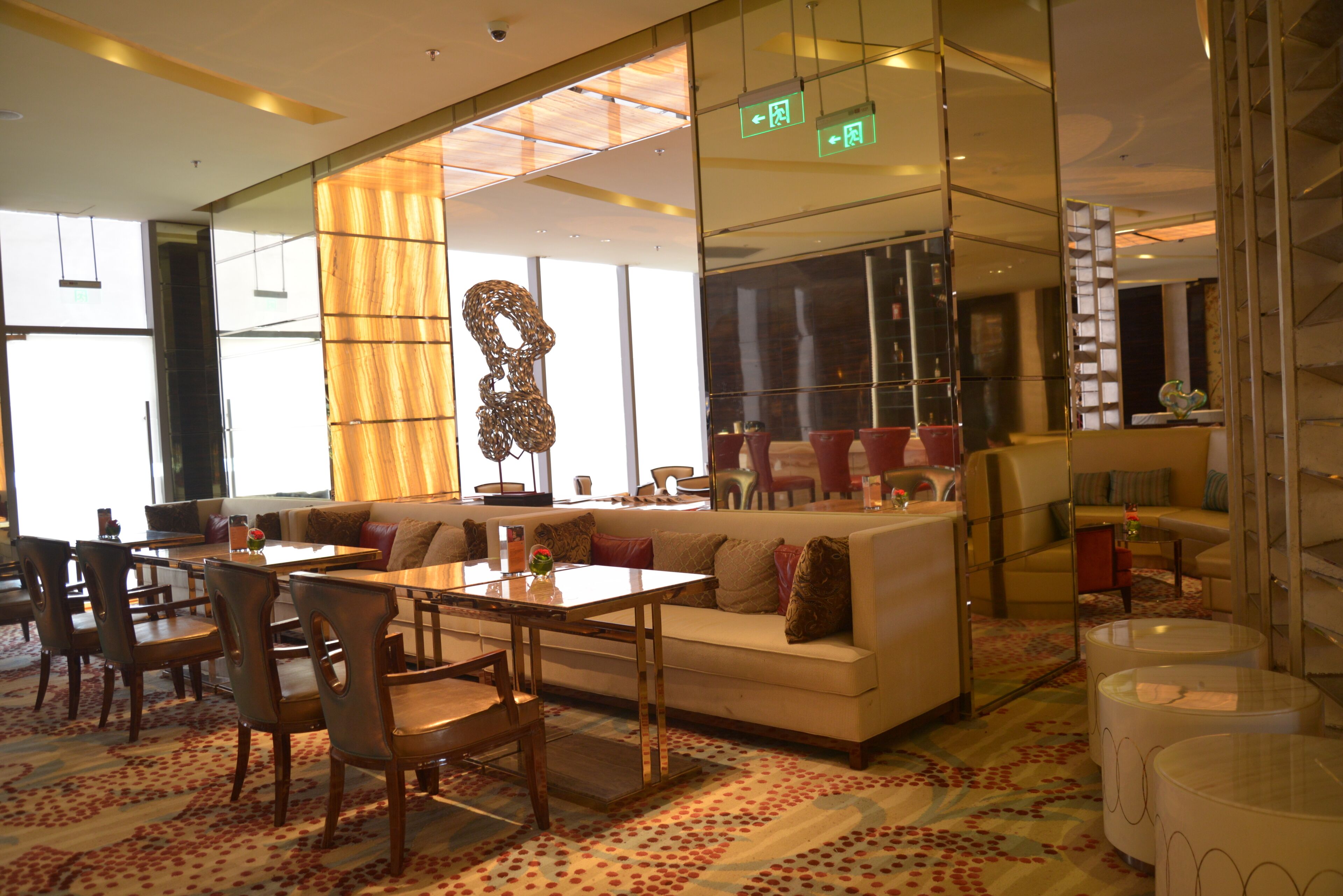 A modern hotel lobby with a seating area, a dining table, and a staircase.