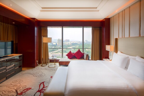 Habitación de hotel con una cama grande, televisión, escritorio y vistas a la ciudad.