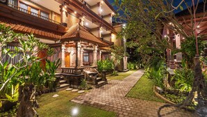 A traditional building with a tiled roof, a central courtyard with a stone pathway, and surrounding greenery. - Suka Beach Inn (Kuta)