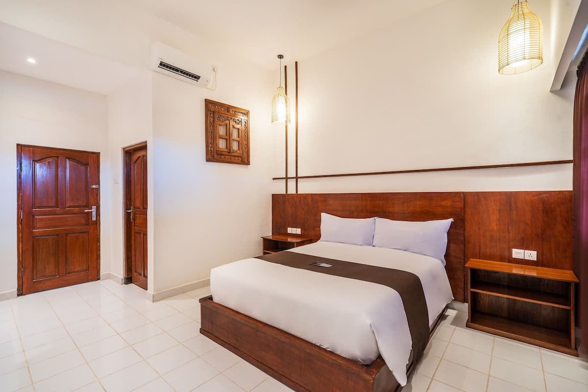 Un dormitorio con cama de madera, mesitas de noche, lámpara colgante y aire acondicionado instalado en la pared.