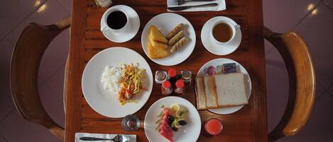 Una mesa de madera con diversos alimentos para el desayuno, como tostadas, huevos y fruta.