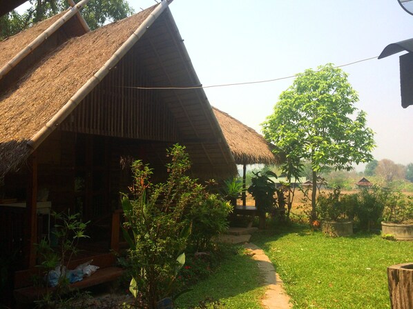 A thatched-roof house with a garden path leading to a wooden bench.