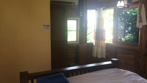 Una habitación con una cama, una ventana con cortinas y una puerta que da a otra habitación.