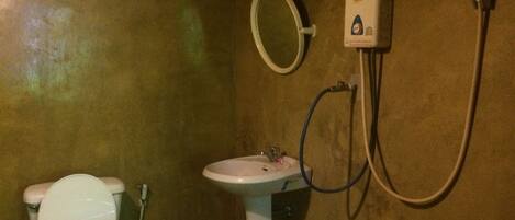 Un baño con inodoro, lavamanos y cabezal de ducha manual.