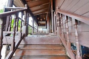 A wooden staircase with balusters leading to a covered area with a view of the street.
