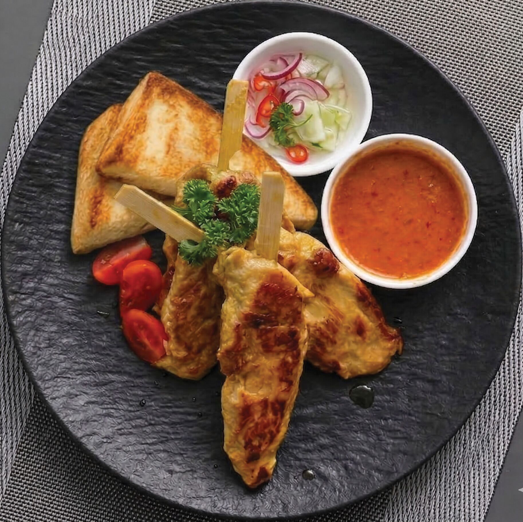 A plate with grilled chicken wings, a side salad, and a bowl of sauce.