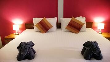 Camera d'albergo con un letto grande, due cuscini, due abat-jour e due asciugamani piegati sul letto.