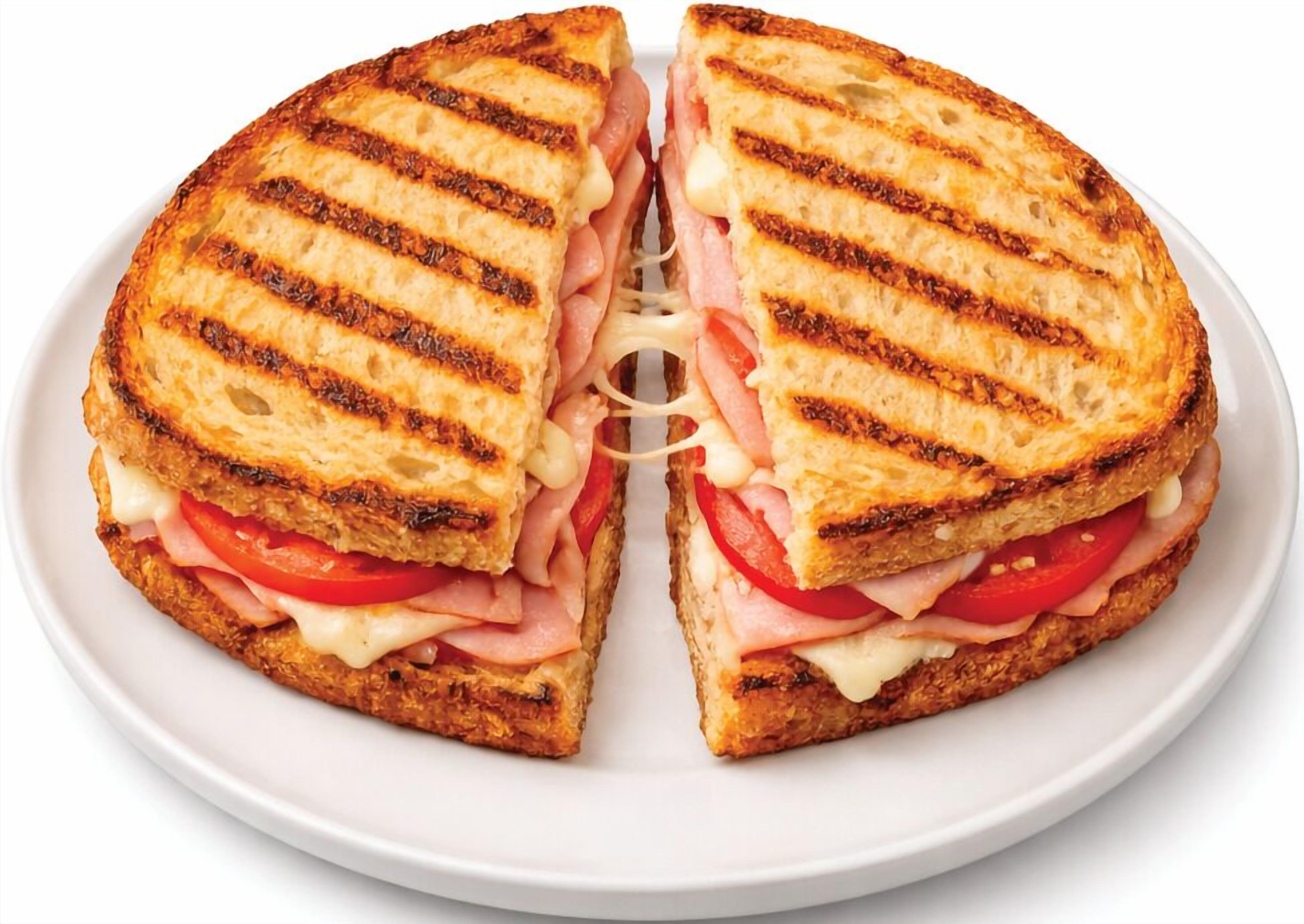 A grilled sandwich cut in half, placed on a white plate.