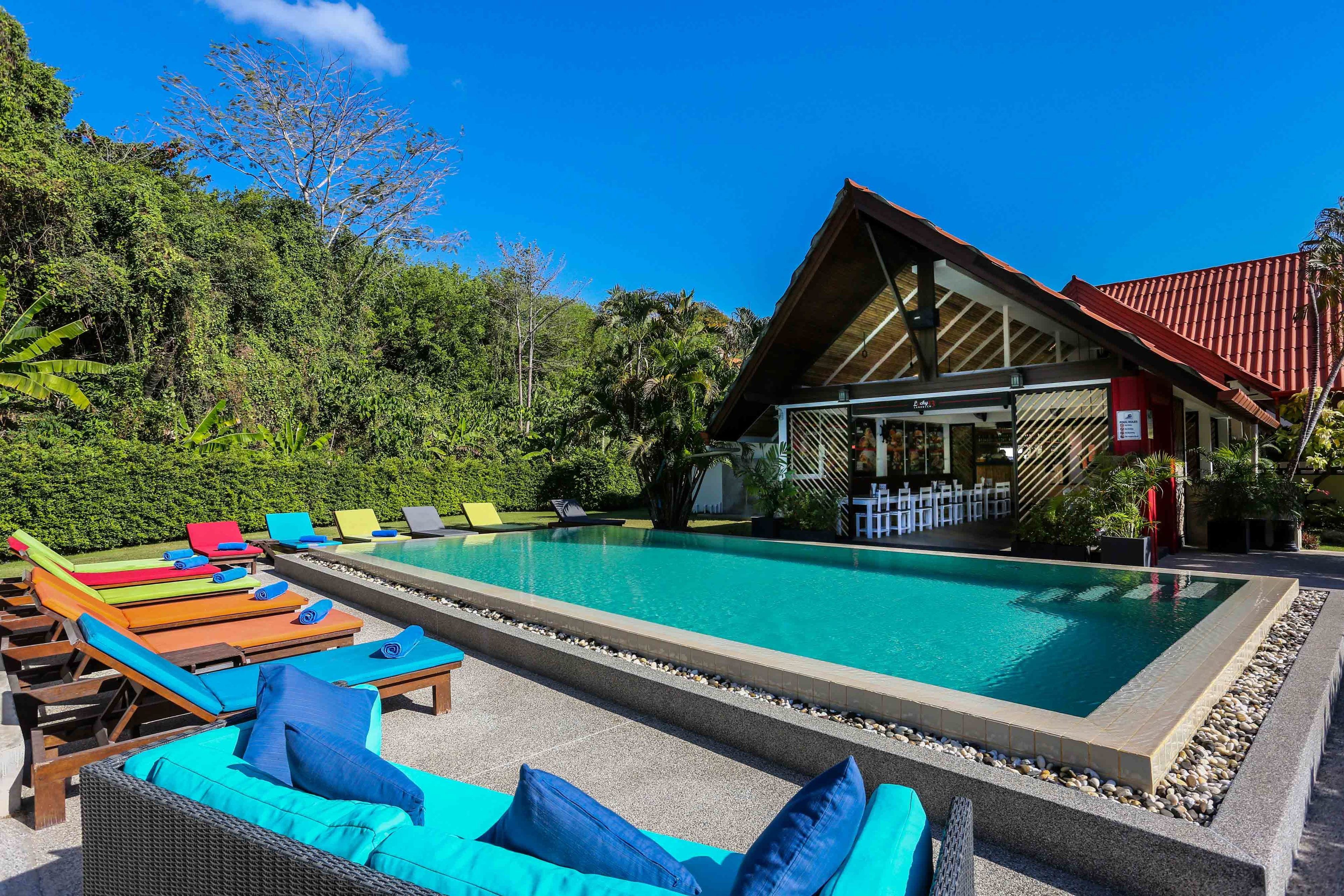 A pool area with lounge chairs and a building with a red roof.