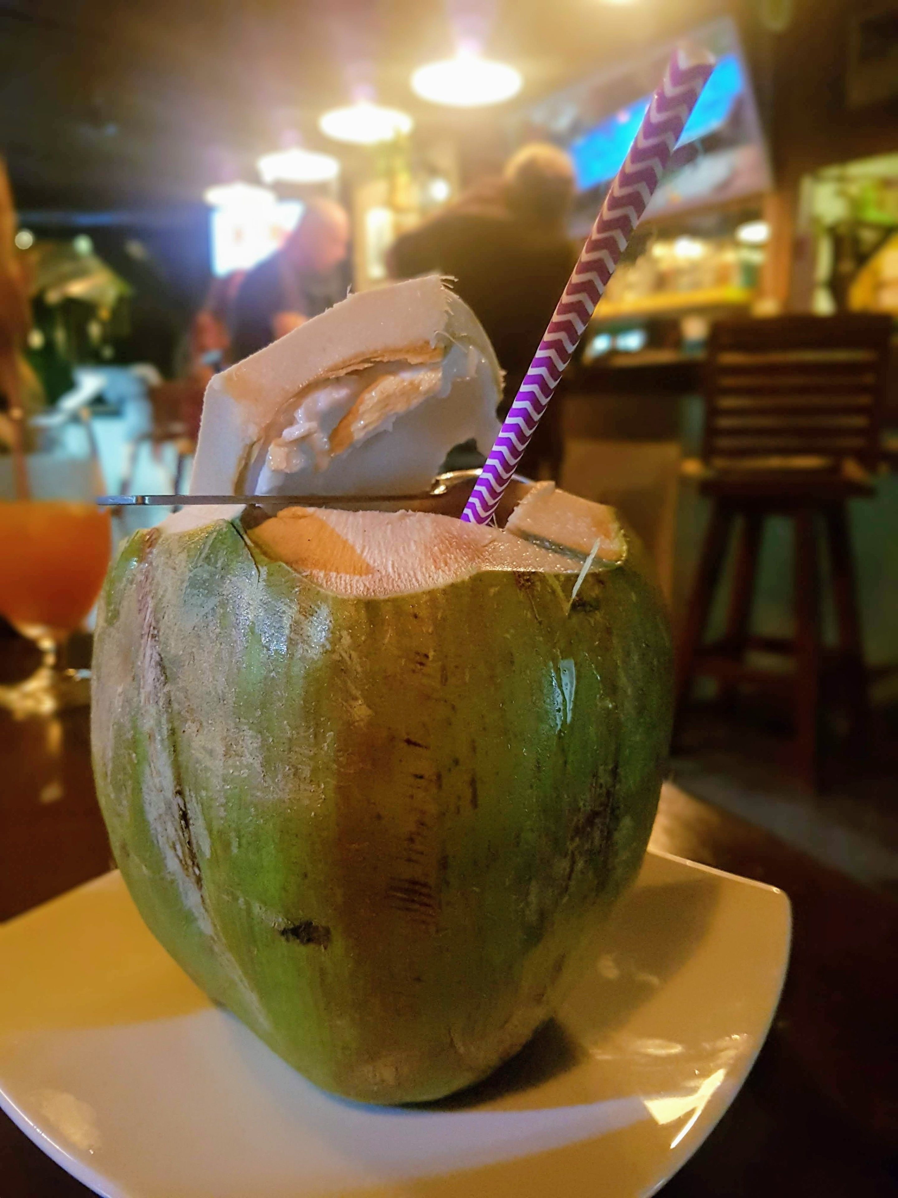Un vaso de coco con pajita sobre un plato blanco.
