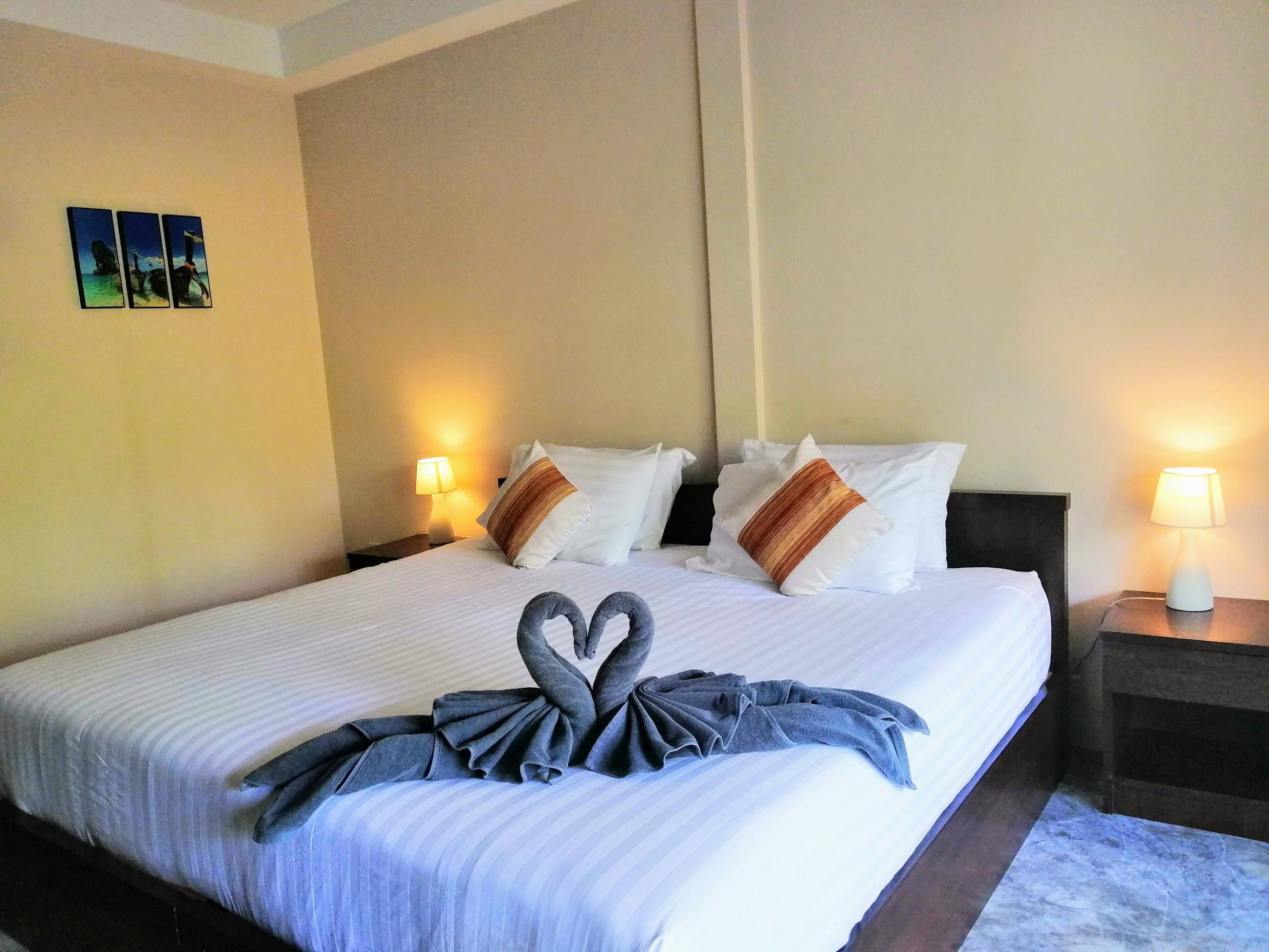 A hotel room with a large bed, two bedside lamps, and a wall-mounted picture.