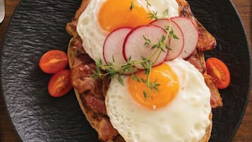 A breakfast dish with eggs, bacon, and tomatoes on toast.